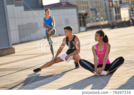 Three athletes doing warm-up in the city Three athletes doing warm-up in the city 76887338