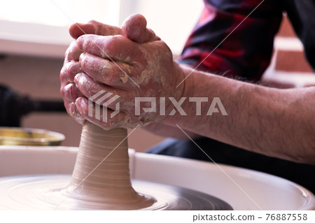 Potter wheel and hands of craftsman making a jug Potter wheel and hands of craftsman making a jug 76887558