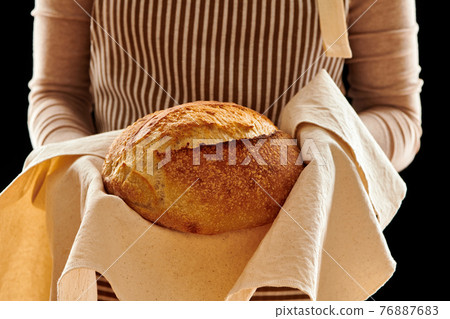 Baker holding loaf of homemade bread 76887683