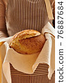 Baker holding loaf of homemade bread 76887684