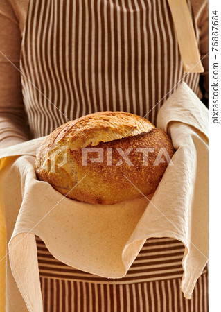 Baker holding loaf of homemade bread 76887684
