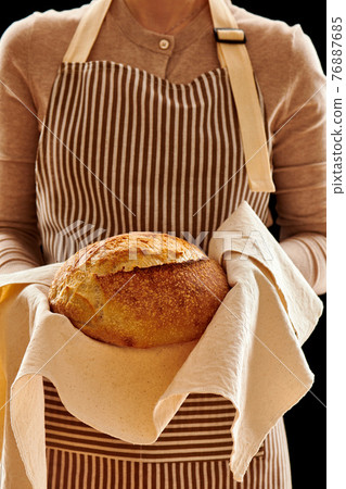 Baker holding loaf of homemade bread 76887685