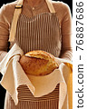 Baker holding loaf of homemade bread 76887686