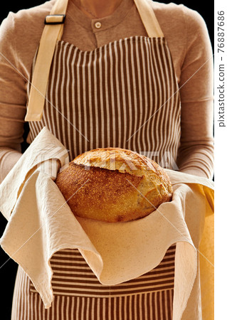 Baker holding loaf of homemade bread 76887686