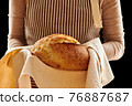 Baker holding loaf of homemade bread 76887687