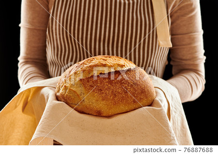 Baker holding loaf of homemade bread 76887688