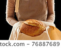 Baker holding loaf of homemade bread 76887689