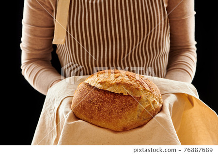 Baker holding loaf of homemade bread Baker holding loaf of homemade bread 76887689