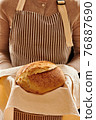 Baker holding loaf of homemade bread 76887690