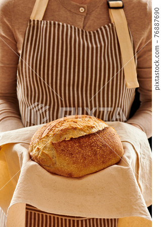 Baker holding loaf of homemade bread 76887690