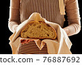Baker holding loaf of homemade bread 76887692