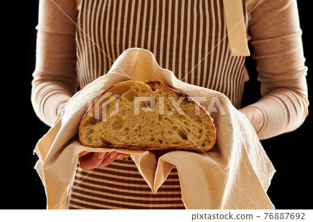 Baker holding loaf of homemade bread Baker holding loaf of homemade bread 76887692