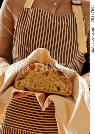 Baker holding loaf of homemade bread Baker holding loaf of homemade bread 76887693