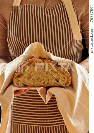 Baker holding loaf of homemade bread 76887694