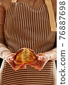 Baker holding homemade bun 76887698