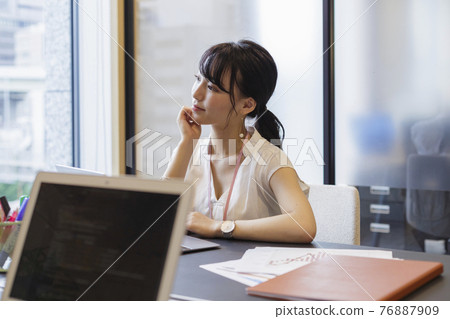 Woman thinking at the office desk 76887909