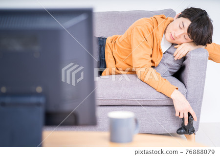 A man lying on the couch tired after playing an internet game (online game) in the room 76888079