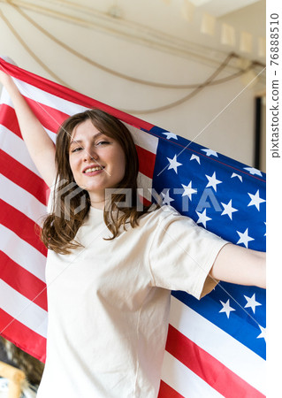 A patriotic woman with a US national flag celebrates, frontview. Independence Day 76888510