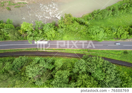 Top down aerial view of winding forest road in green mountain spruce woods. 76888769