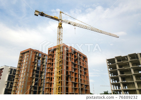 High-rise residential apartment buildings and tower crane under development on construction site. Real estate development. High-rise residential apartment buildings and tower crane under development on construction site. Real estate development. 76889232