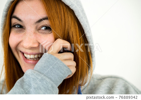 Close up portrait of happy smiling young redhead woman wearing warm hoodie pullover. Close up portrait of happy smiling young redhead woman wearing warm hoodie pullover. 76889342