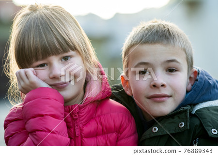 Two children boy and girl fooling around having fun together outdoors on sunny fall day. Happy childhood concept. Two children boy and girl fooling around having fun together outdoors on sunny fall day. Happy childhood concept. 76889343