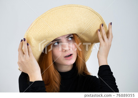 Portrait of funny redhead woman in bag yellow straw hat. 76889355