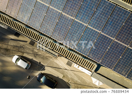 Aerial view of solar photovoltaic panels on a roof top of residential building block for producing clean electric energy. Autonomous housing concept. 76889434