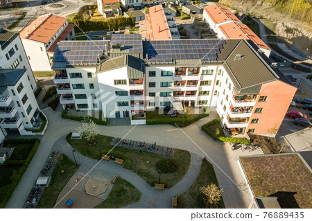 Aerial view of solar photovoltaic panels on a roof top of residential building block for producing clean electric energy. Autonomous housing concept. 76889435