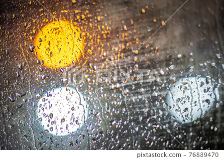 Abstract colorful background of glass surface with water drops and blurred city lights. Abstract colorful background of glass surface with water drops and blurred city lights. 76889470