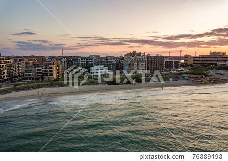 Aerial view of Pomorie city that is located on Black Sea shore. Top view of sand beaches with many hotel buildings and tourist infrastructure. Aerial view of Pomorie city that is located on Black Sea shore. Top view of sand beaches with many hotel buildings and tourist infrastructure. 76889498