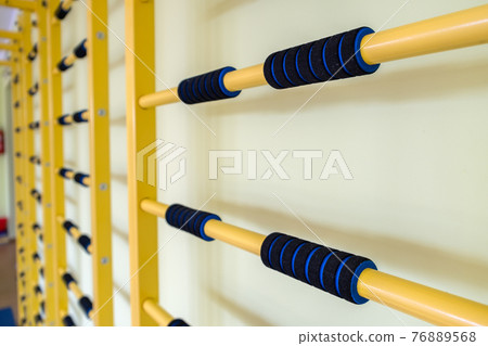 A wall with ladder bar for fitness training inside sports gym room in a school. 76889568
