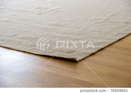 Close up of crumpled carpet laying on parquet wooden floor. Close up of crumpled carpet laying on parquet wooden floor. 76889681
