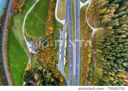 Top dawn aerial view of freeway speed road between yellow autumn forest trees in rural area. 76889708