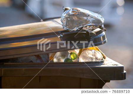 Closeup of trash can container full of garbage. Closeup of trash can container full of garbage. 76889710