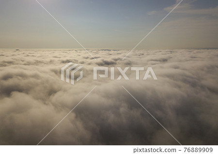 Aerial view over white clouds and clear blue sky. 76889909