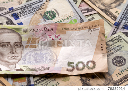 Money and finances concept. Ukrainian national currency bill worth five hundred grivna on colorful abstract background of American dollar different banknotes. Money and finances concept. Ukrainian national currency bill worth five hundred grivna on colorful abstract background of American dollar different banknotes. 76889914