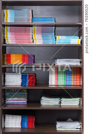 Bookcase with textbooks and notebooks neatly laid out on the shelf. Bookcase with textbooks and notebooks neatly laid out on the shelf. 76890020