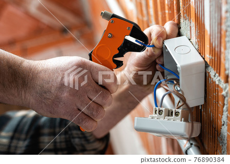 Electrician at work on a residential electrical system. Electricity. 76890384