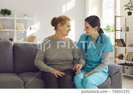 Supportive young doctor and happy senior patient sitting on sofa at home and talking Supportive young doctor and happy senior patient sitting on sofa at home and talking 76891391