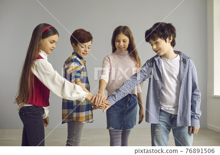 Group of children stand and join hands together studio shot on copy space Group of children stand and join hands together studio shot on copy space 76891506