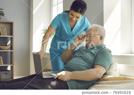Friendly smiling nurse showing old senior man patient analysis result on laptop Friendly smiling nurse showing old senior man patient analysis result on laptop 76891628