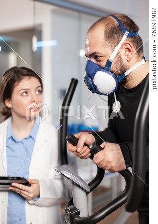 Performance athlete with electrodes attached running on cross training wearing mask 76891982