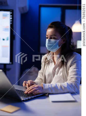 Project manager with protection face mask using professional laptop 76892031