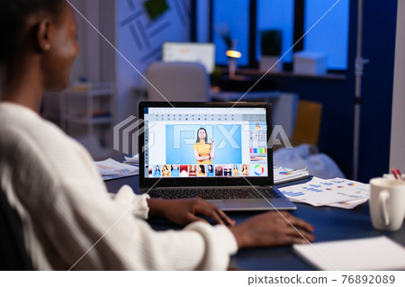 Dark skin freelancer retoucher woman working overtime on editing software Dark skin freelancer retoucher woman working overtime on editing software 76892089