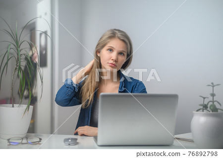 A girl with a laptop is studying at an online school. White room background 76892798