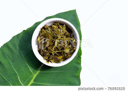 Senna siamea boiled leaves in white bowl on taro leaf 76892820