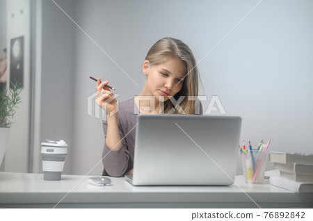 A girl with a laptop is studying at an online school. White room background A girl with a laptop is studying at an online school. White room background 76892842