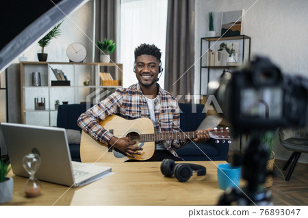 Inspired afro man playing guitar and recording video Inspired afro man playing guitar and recording video 76893047