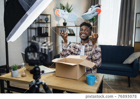 Afro man unboxing sneakers for creating video content Afro man unboxing sneakers for creating video content 76893078